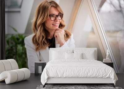 Smiling middle aged business woman standing with arms crossed by the window Wall mural