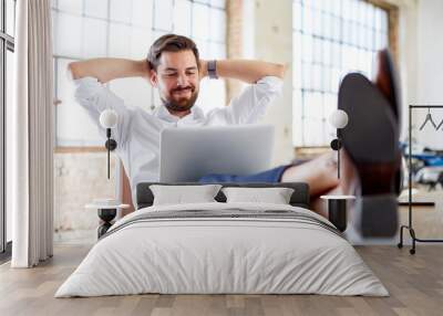 young businessman with legs on the desk Wall mural