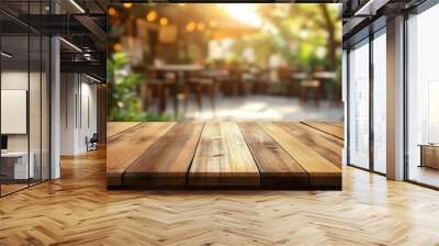 Empty wooden table with blurred background of outdoor cafe with sunlight and greenery. Wall mural