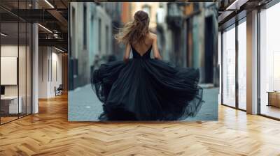 Woman in a black dress walking down a city street. Wall mural