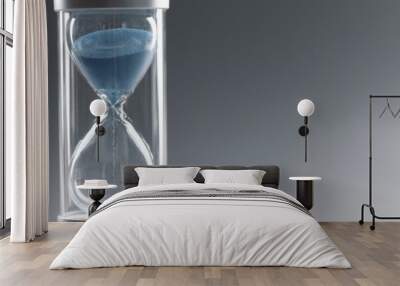 Closeup of hourglass with blue sand on gray background Wall mural