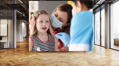 Doctor taking pcr swab from nose of little girl using cotton swab at clinic Wall mural