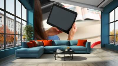 female hand holds tablet in home setting while Wall mural