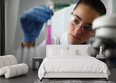 Female scientist in laboratory holds test tube with purple liquid in her hand. Human DNA research test and cloning Wall mural