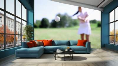 Golf ball against background of hitting woman closeup. Active healthy lifestyle concept Wall mural