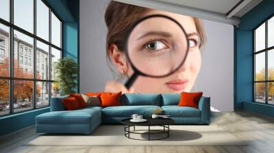 Inquisitive young woman looking through magnifying glass Wall mural