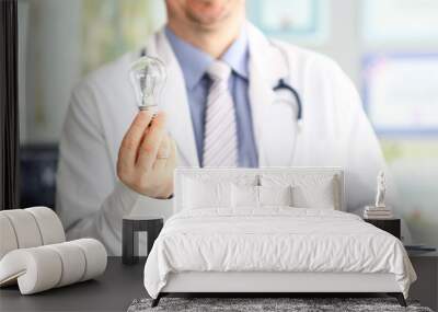 Male doctor hand holding lightbulb as bright idea invention symbol closeup Wall mural