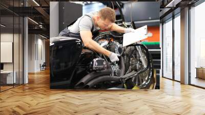 Male mechanic diagnoses parts on motorcycle at service center Wall mural