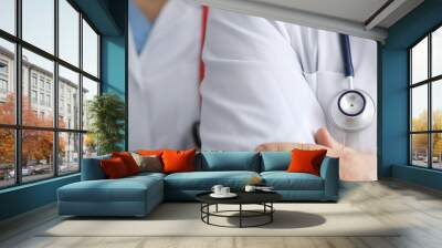 Man and woman doctors with phonendoscope around their necks stand with hands folded closeup. Work in private medical centers concept. Wall mural