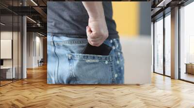 Man pulling out wallet from back pocket of jeans closeup. Keeping money concept Wall mural