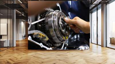 Mechanic repairs motor and chain of motorcycle in workshop. Motorcycle engine repair diagnostics concept Wall mural