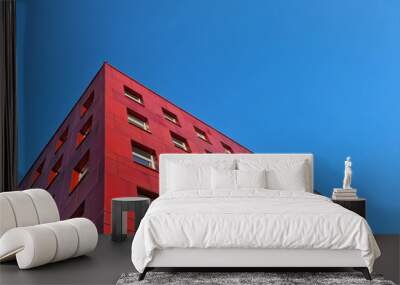 multi-storey red building standing against blue sky background Wall mural