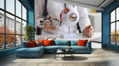 Ophthalmologist holds glasses for selection of lenses and anatomy of human eye Wall mural