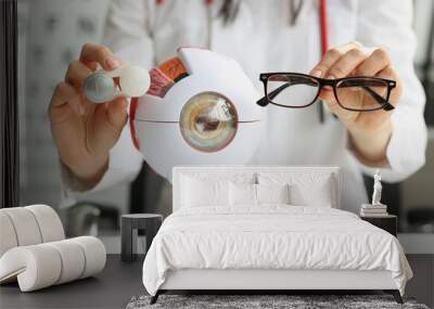 Optometrist woman holding glasses near anatomical model eye Wall mural