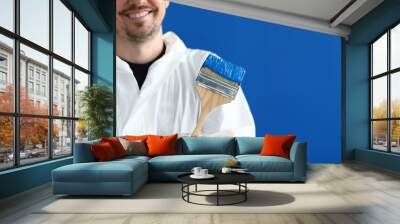 Smiling master house painter holds paintbrush with blue paint Wall mural