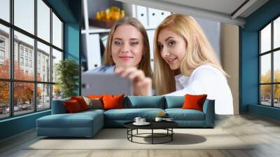 Two businesswomen in the office smile and do selfie on a smartphone during a break to have coffee Wall mural