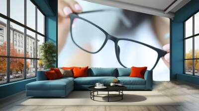 Woman holding glasses for vision, close-up Wall mural