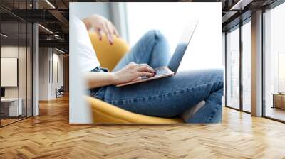 Woman sitting in chair with laptop on her lap closeup. Self isolation concept Wall mural