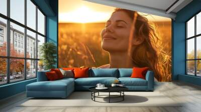 beauty of a woman standing amidst fields at sunset, her calm and happy expression illuminated by the soft golden light, eyes closed as she savors the tranquility of the moment Wall mural