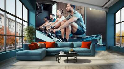 Fitness, class and man on rowing machine for health, wellness and body workout in gym. Exercise, healthy people and strong athlete on ergometer equipment for arms, cardio training and muscle growth Wall mural