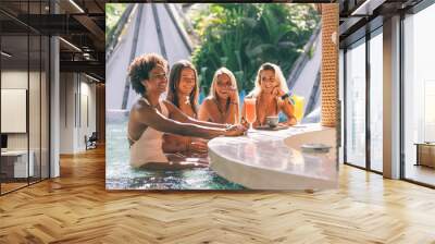 Group of girl friends enjoying coffee and fresh juice at pool bar in hotel in Seminyak, Bali Wall mural