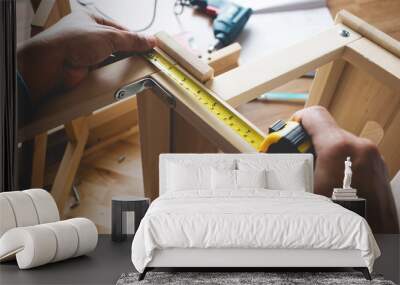 Man assembly wooden furniture,fixing or repairing house with tape measures Wall mural