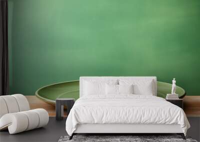 green earthenware plate on a green background Wall mural