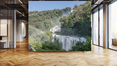 rainbow in mist at tall waterfall amidst lush green vegetation, Marmore, Italy Wall mural