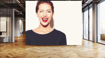 cheerful smiling winking fashion girl going crazy in casual black clothes with red lips on white background Wall mural