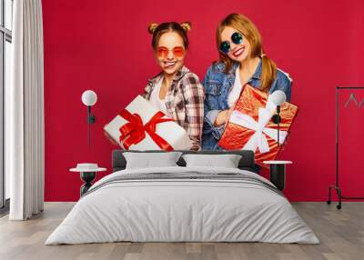 Christmas, x-mas, concept.Two smiling beautiful women in stylish clothes.Girls posing on red background.Models with big gift boxes.Having fun,ready for celebration.Bright holiday of best friends Wall mural