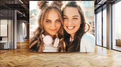 Closeup portrait of two young beautiful smiling hipster female in trendy summer white t-shirt clothes.Sexy carefree women posing on street background. Positive models having fun and hugging Wall mural