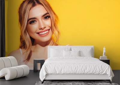 Fashion beauty portrait of young smiling blond woman with natural stylish  makeup and perfect clean skin. Sexy model with long curly hair posing in studio on  yellow background Wall mural