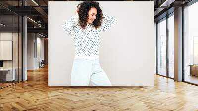 Portrait of beautiful smiling model with afro curls hairstyle dressed in summer hipster clothes.Sexy carefree girl posing in studio on gray background.Trendy funny and positive woman Wall mural