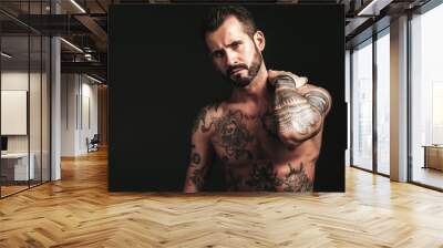 Portrait of handsome confident stylish hipster lambersexual model. Sexy modern man. Naked torso with tattoos.Fashion male posing in studio on dark background Wall mural