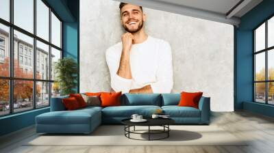 Portrait of handsome smiling hipster lumbersexual businessman model wearing casual summer white clothes. Fashion stylish man posing against gray wall Wall mural