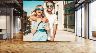 Portrait of smiling beautiful woman and her handsome boyfriend. Woman in casual summer jeans dress. Happy cheerful family. Female having fun. Couple posing on the street background in sunglasses Wall mural