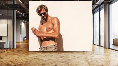 Portrait of sporty handsome strong man. Healthy athletic fitness model posing near white wall in jeans. Confident sexy fashion male with naked nude torso. Lambersexual outdoors in sunglasses Wall mural