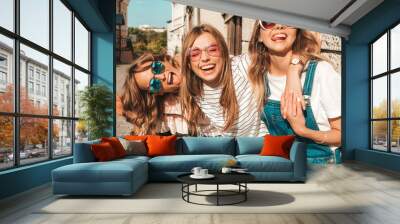 Portrait of three young beautiful smiling hipster girls in trendy summer clothes. Sexy carefree women posing near wall in the street.Positive models having fun in sunglasses Wall mural