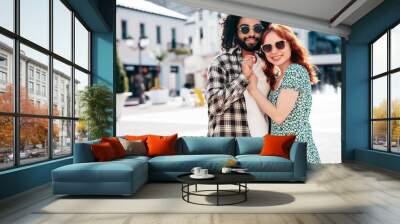 Smiling beautiful redhead  woman and her handsome boyfriend. Model in casual summer clothes. Happy cheerful family. Female having fun. Couple posing in the street at sunny day. In sunglasses Wall mural