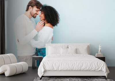 Smiling beautiful woman and her handsome boyfriend. Happy cheerful multiracial family having tender moments on grey background  in studio. Multiethnic models hugging. Embracing each other.Love concept Wall mural