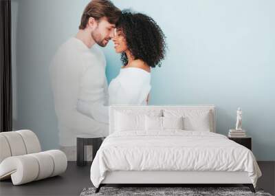 Smiling beautiful woman and her handsome boyfriend. Happy cheerful multiracial family having tender moments on grey background  in studio. Multiethnic models hugging. Embracing each other.Love concept Wall mural