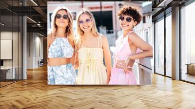 Three young beautiful smiling hipster female in trendy summer stylish clothes. Sexy carefree women posing in the street. Positive models having fun, hugging and going crazy, in sunny day, sunglasses Wall mural