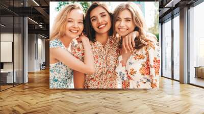 Three young beautiful smiling hipster girls in trendy summer sundress.Sexy carefree women posing on the street background. Positive models having fun and hugging.Walking after shopping Wall mural