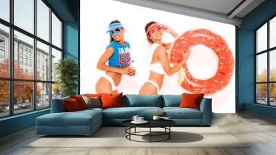 Two beautiful sexy smiling hipster women in white summer underpants and topic.Girls in sunglasses,transparent visor cap.Models drinking fresh cocktail smoozy drink with donut lilo inflatable mattress Wall mural