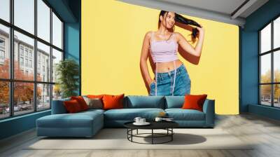 Young beautiful smiling female in trendy summer jeans and top clothes. Carefree woman posing near yellow wall in studio. Sexy positive model having fun indoors. Cheerful and happy Wall mural