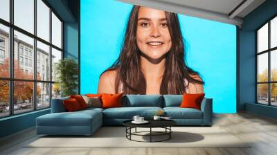 Young beautiful woman looking at camera. Trendy girl in casual summer clothes. Funny and positive female posing near blue wall in studio Wall mural