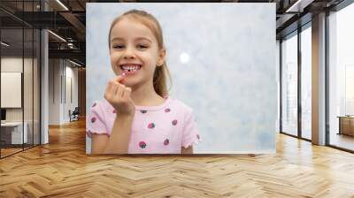 Girl child shows her mouth without one lost milk tooth and smiles. A child in the bathroom holds a milk tooth in his hand and smiles. Free space for text Wall mural