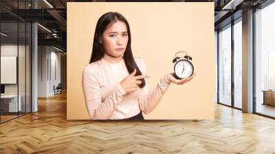 Angry young Asian woman point to a clock. Wall mural