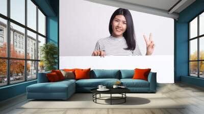 Young Asian woman show victory sign with blank sign. Wall mural