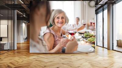 A big family sitting at a table on a indoor birthday party, clinking glasses. Wall mural